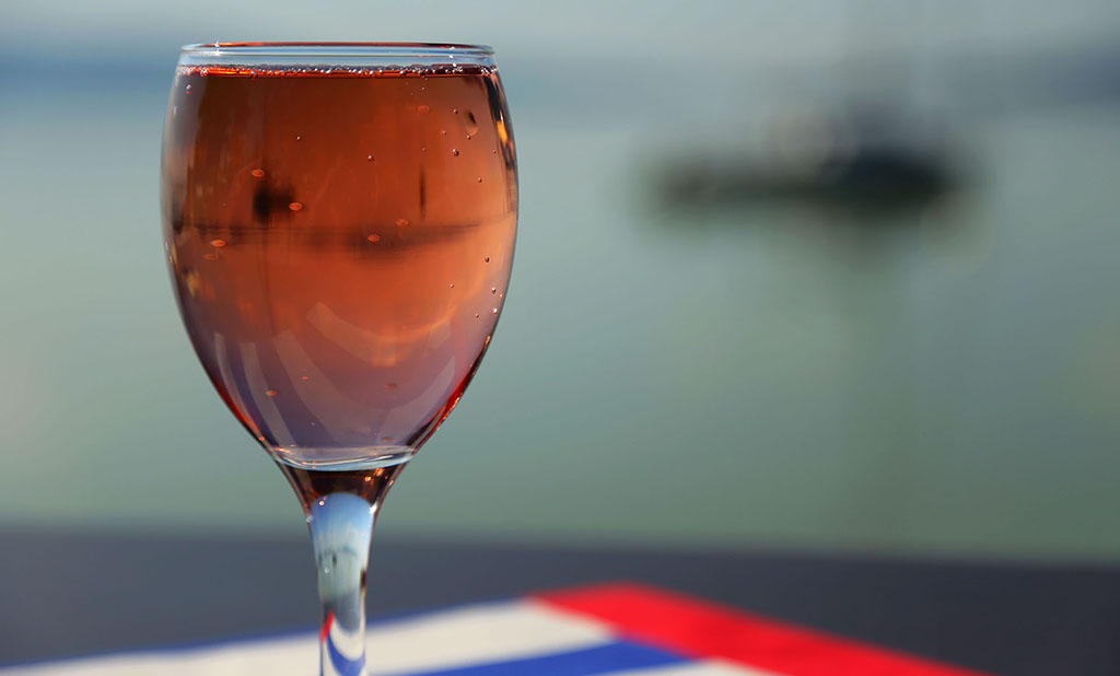 Egy borospohár rosé bor a balatoni panorámával